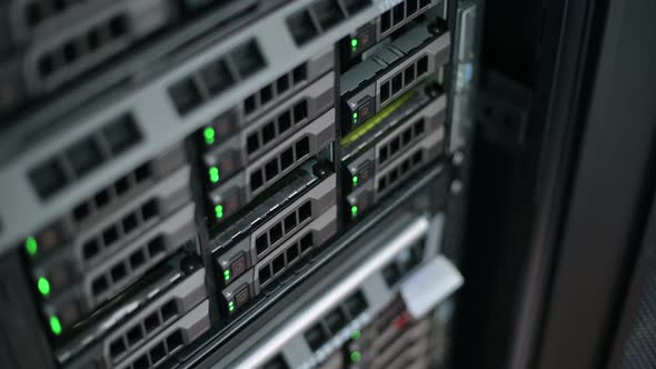 camera zooms in on a hard drive in a server cabinet. Bokeh and blinking lights alt