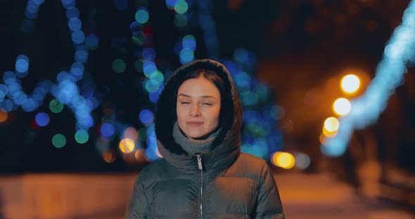 Beautiful Woman Walks Along a Night Street New Year's City in the Lights of Garlands alt