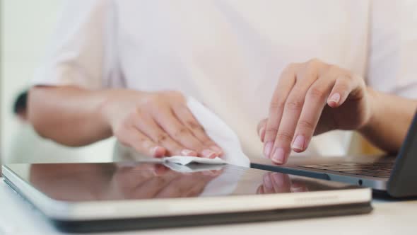 Asian woman using alcohol spray on tissue clean tablet before open for protect coronavirus. alt