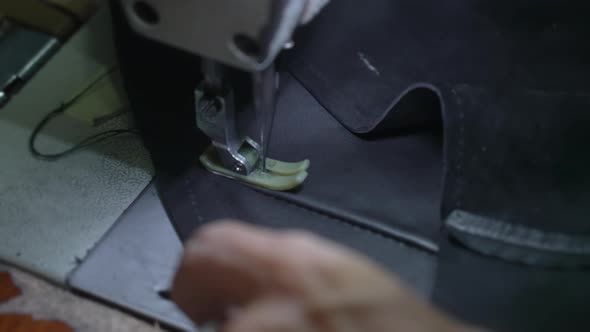 Closeup of Old Hands with a Silver Ring of a Tailor Who Makes Stitch on Black Leather Jacket on alt