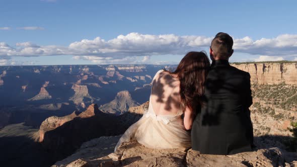 Bride and groom sitting on the edge of Grand Canyon South Rim, Arizona, USA alt
