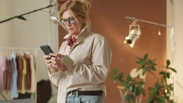 Mature Woman Using Smartphone at Work in Photo Studio alt
