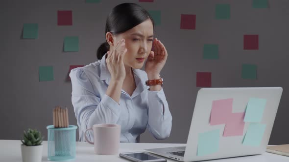 Asian woman working on a laptop tired and has eye pain sitting