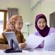 Two muslim women wearing hijab working together with using laptop tablet and paper showing chart - VideoHive Item for Sale