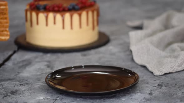 Piece of Layer Caramel Cake with Cream and Fresh Berries on Black Plate