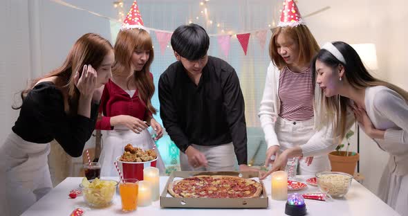 Slow motion of Happy young Asian friends enjoying pizza in night party. alt