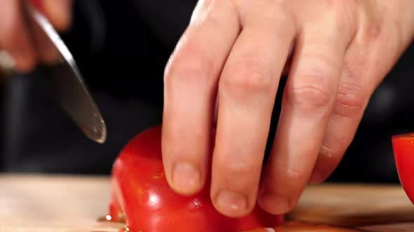 Hands is Cutting a Tomato with a Knife on Wooden Board Closeup