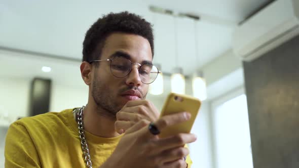 An African Young Man Uses a Smartphone alt