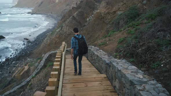 Young Man Tourist Goes Down the Long Stairs to the Famous Volcanic Black Sand Beach Benijo in the alt