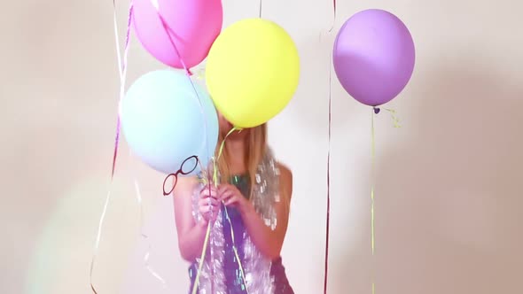 Happy blonde woman jumping with balloons in photo booth alt