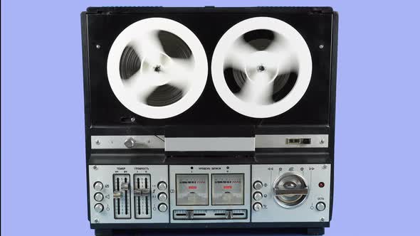 Rewinding Tape On An Old Reel To Reel Recorder On A Blue Background.