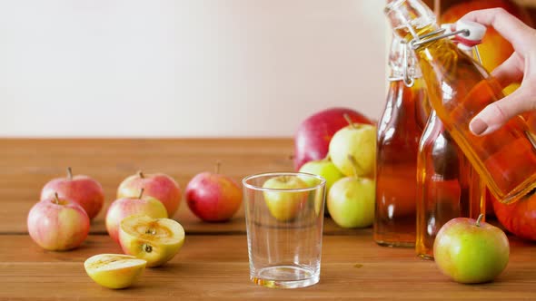 Hand Pouring Apple Juice From Bottle To Glass alt