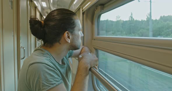 Young Attractive Tourist Looker Out of the Window of a Moving Train at Sunset