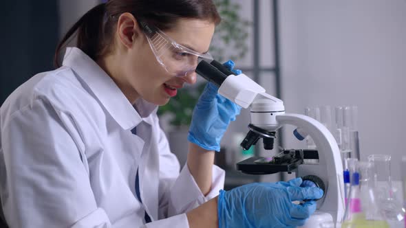 Biological Laboratory for Researching Woman is Viewing Sample Under Microscope alt