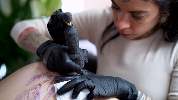 Crop artist drawing tattoo on body of client in shop alt