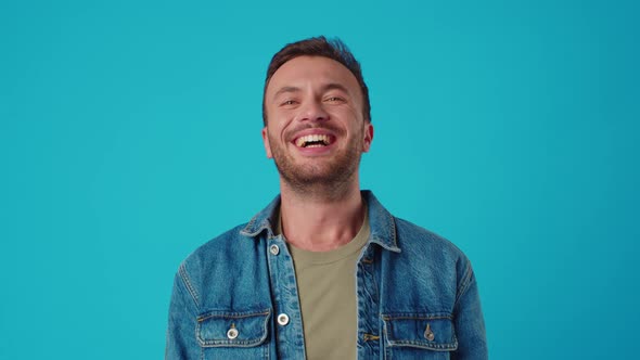 Young Caucasian Man Smiling Against Blue Studio Background