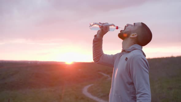 Runner Drinking Water After Workout in Field