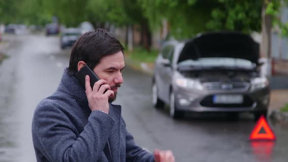 Breakdown Car accident in rain Young upset business man standing at broken car calling for repair