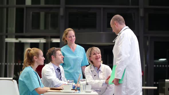 Doctor shaking hands and interacting with colleagues in conference room alt