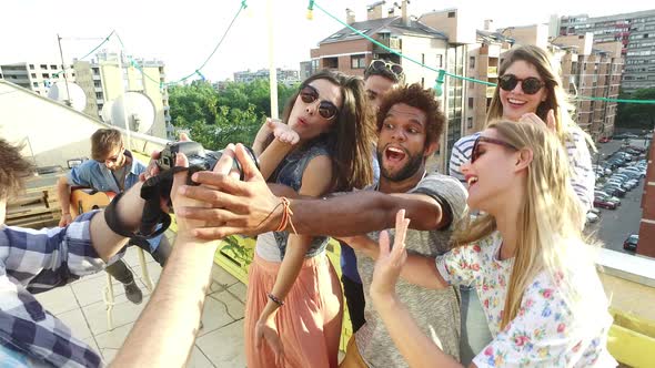 Group of people taking photos while musician playing guitar on rooftop terrace alt