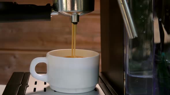 Morning Espresso Coffee is Poured Into a White Cup From the Coffee Machine alt