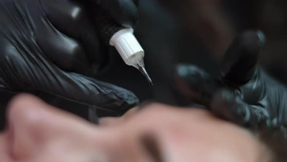 Closeup Microblading Pen in Hand of Tattoo Master Filling Eyebrow Skin with Pigment alt