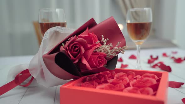 Bunch of flowers, roses in box lying on the table of romantic dinner with two glasses of wine.