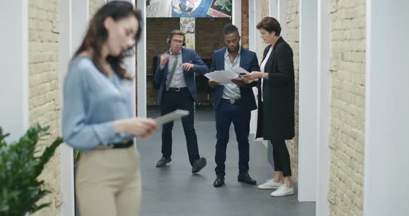 Happy Young Man in Headphones Dancing As Walking Along Office Corridor Greeting Coworkers. Cheerful alt