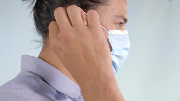Man facing right puts on blue face mask, Extreme Closeup Profile alt