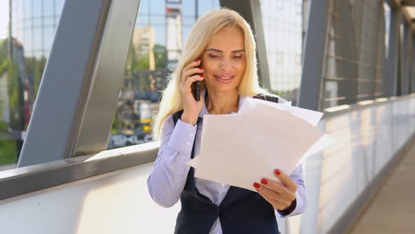 Portrait of 50 Years Business Woman with Documents Calling Phone Outdoor alt