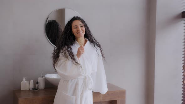 Funny Carefree Cheerful Young Curly Woman in Bathrobe Dancing in Bathroom to Favorite Music Sing alt