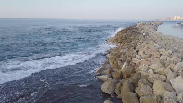 Deep blue waters of the Mediterranean gently roll over the breakwater while Jaffa and Tel Aviv sunse alt