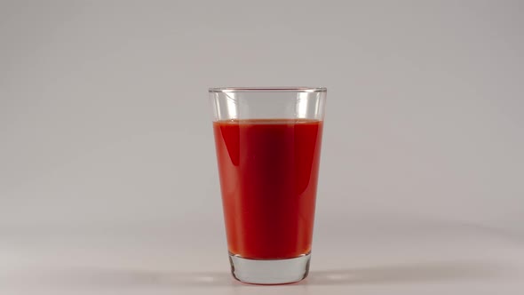 Drinking of tomato juice from a glass on a white background
