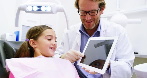 Dentist showing digital tablet to young patient alt