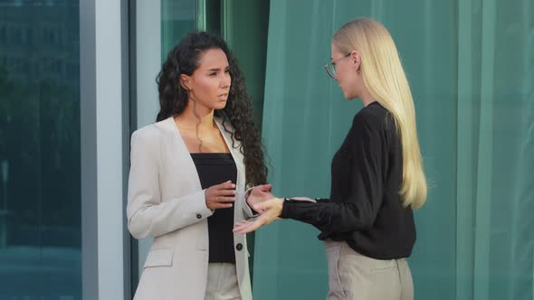 Two Serious Diverse Female Colleagues Team Talking Near Modern Office Building East Indian alt