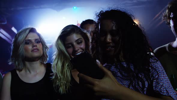 Group of friends reviewing pictures on mobile phone at a concert 4k alt