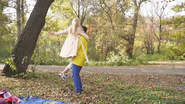 Happy Couple Having Fun in the Autumn Park a Man Hugs and Circles a Woman Laughing and Smiling alt