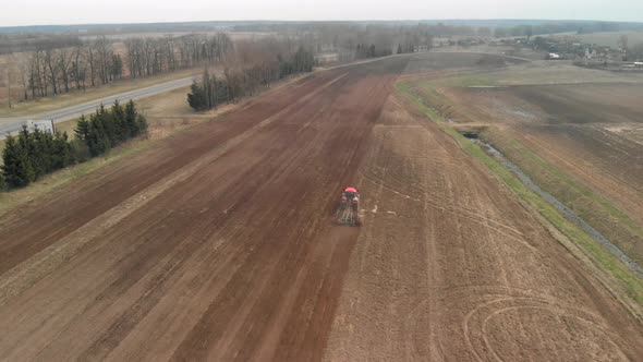 Tractor Cultivates Farmland Along the Highway and Reclamation Ditch alt