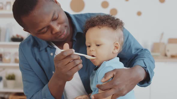 Young African Man Feeding Infant alt