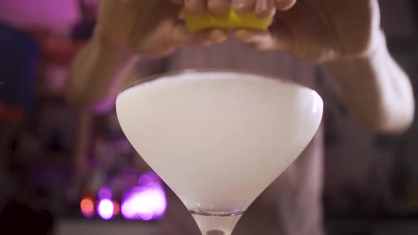Bartender Squeezes Lemon Rind Into a Glass with a French 75 Cocktail