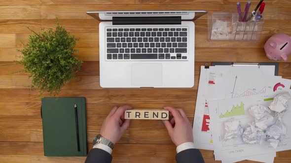 Word trend consists of wooden cubes letters on office table next to notebook. alt