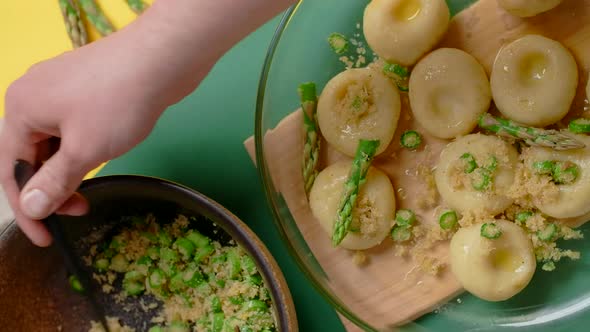 Vertical Flat Lay Video the Cook Ads Chopped Asparagus to the Plate of Cooked Potato Dumplings