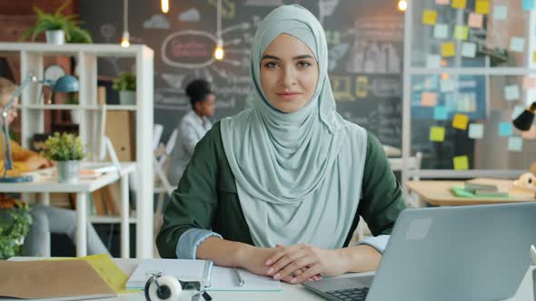 Slow Motion Portrait of Beautiful Muslim Woman in Hijab Sitting at Desk at Work alt