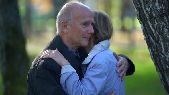 Old Spouses Are Embracing in Park at Autumn Day, Happy Old Age and Long Marriage, Husband and Wife alt
