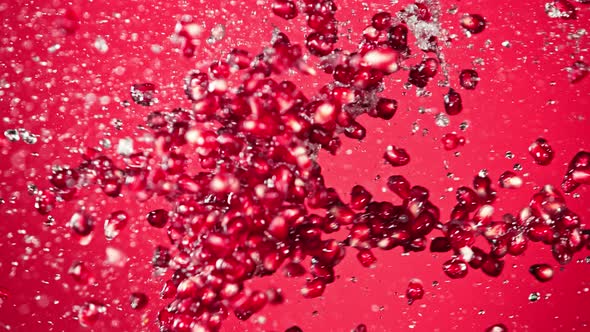 Super Slow Motion Shot of Fresh Pomegranate Seeds and Water Side Collision on Red at 1000Fps alt