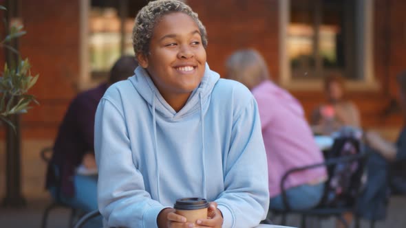 Happy African Student Drinking Coffee Sitting at Street Cafe Outdoors alt