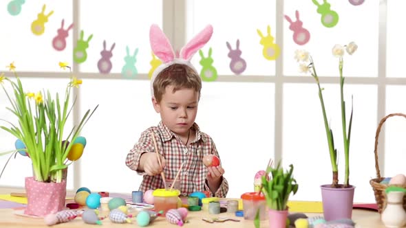 Happy Child Wearing Bunny Ears Painting Eggs on Easter Day
