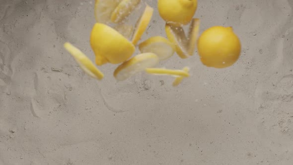 Whole Lemons with Cut Pieces of Lemon Fly and Collide and Fall on the Sand alt