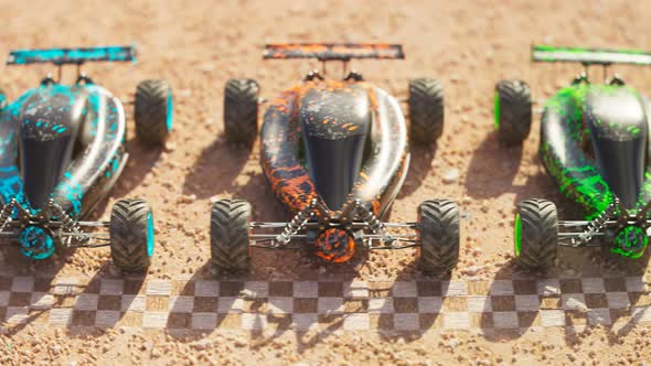 Multiple colourful remote-controlled buggy cars on start line in the desert. alt