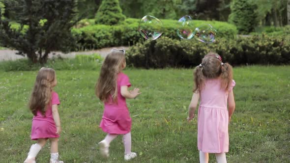 Happy Little Girls Playing in Garden and Playing Bubbles